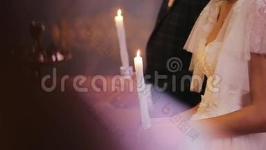 在教堂举行的燃烧蜡烛的近距离拍摄。 新婚夫妇新郎穿西装新娘穿<strong>白裙</strong>子
